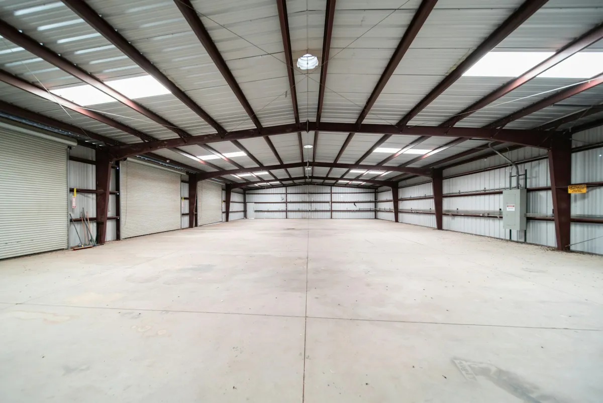 Inside a large empty steel-framed warehouse with a clear-span roof