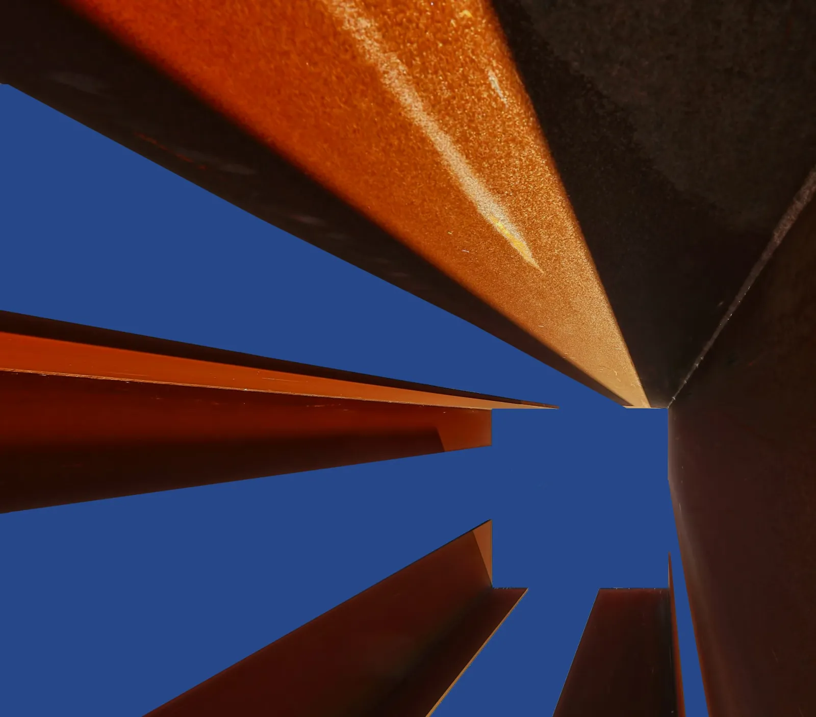 Looking up between steel angle sections towards a blue sky